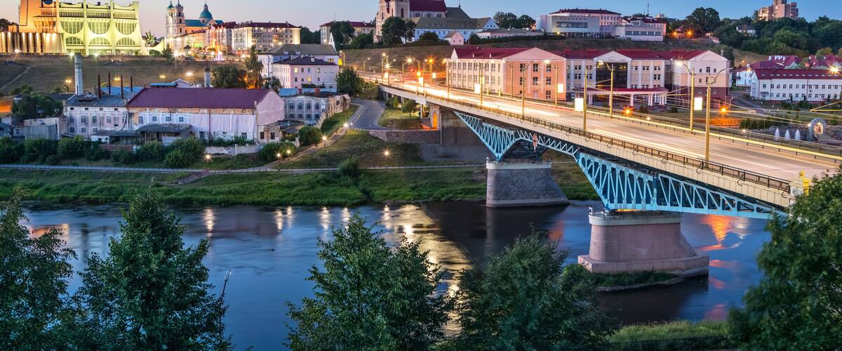 A river with a bridge, buildings, and a tower in the background.