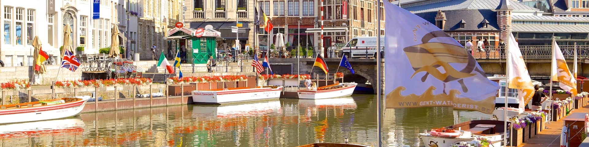 A canal with boats, historic buildings, and a castle in the background.