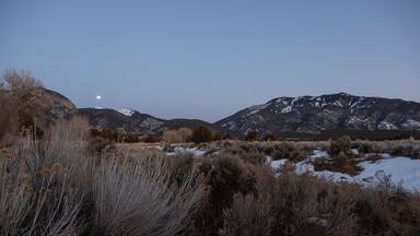 The full moon rises over mountains in the winter