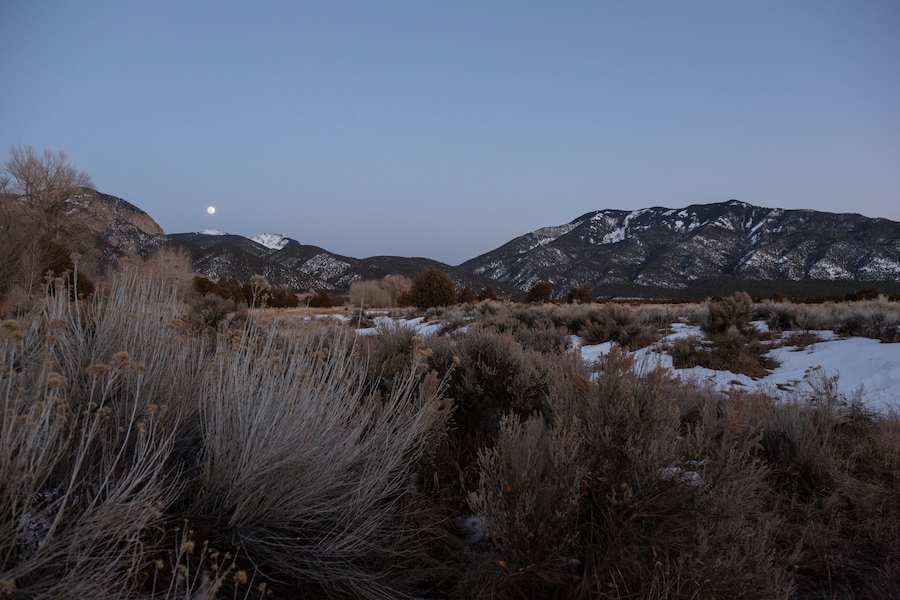 The full moon rises over mountains in the winter