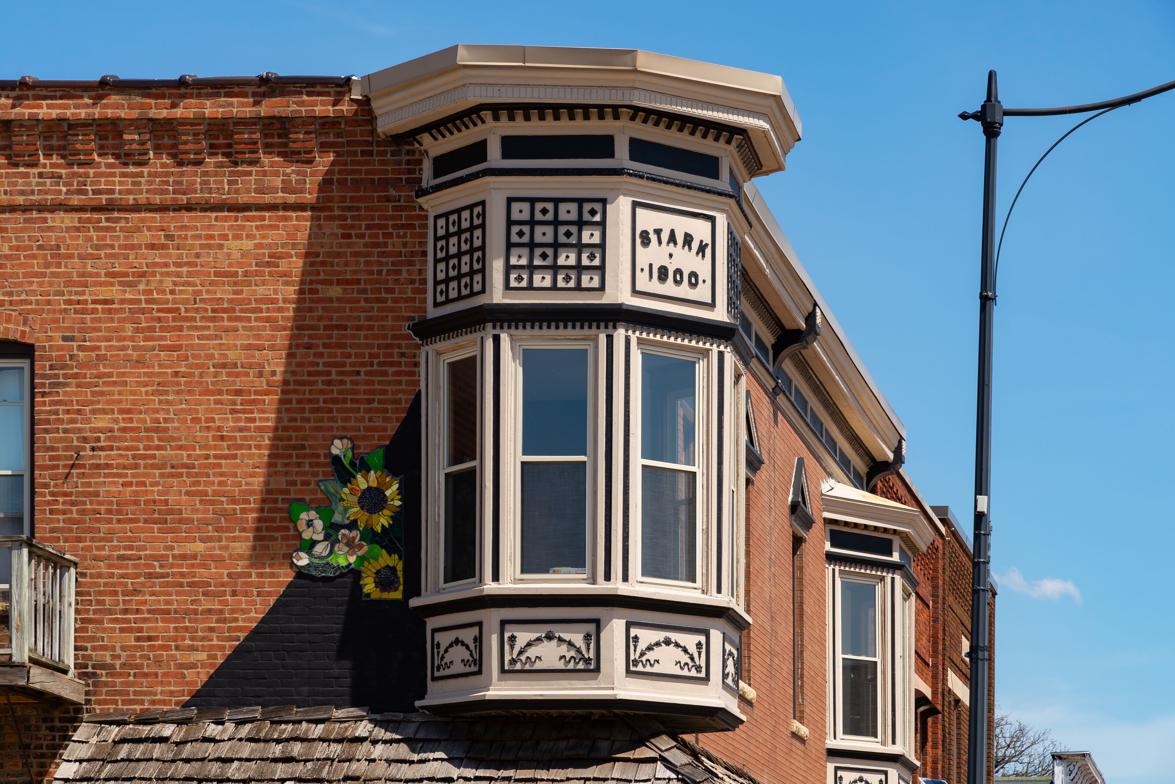 A corner bay window with a decorative frame and a sign reading "STARK 1900."