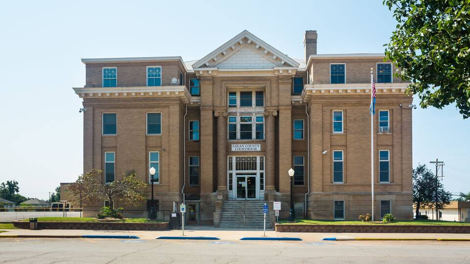 A large brick courthouse with a central entrance and steps leading up to it.