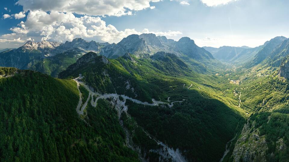 A mountainous landscape with a winding road through a valley.