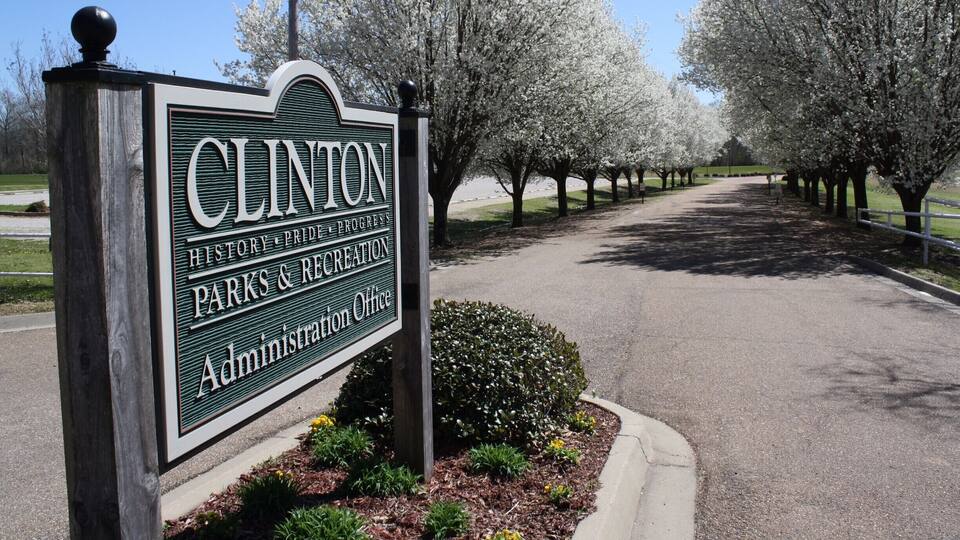 A sign for Clinton History & Recreation Parks & Recreation Administration Office surrounded by blooming trees.