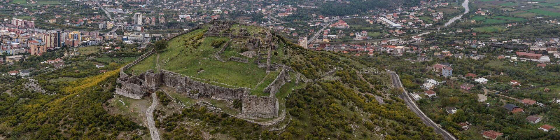 Aerial panorama of Lezhë Castle overlooking the city, Drin River and Adriatic coastline under soft cloudy light.
