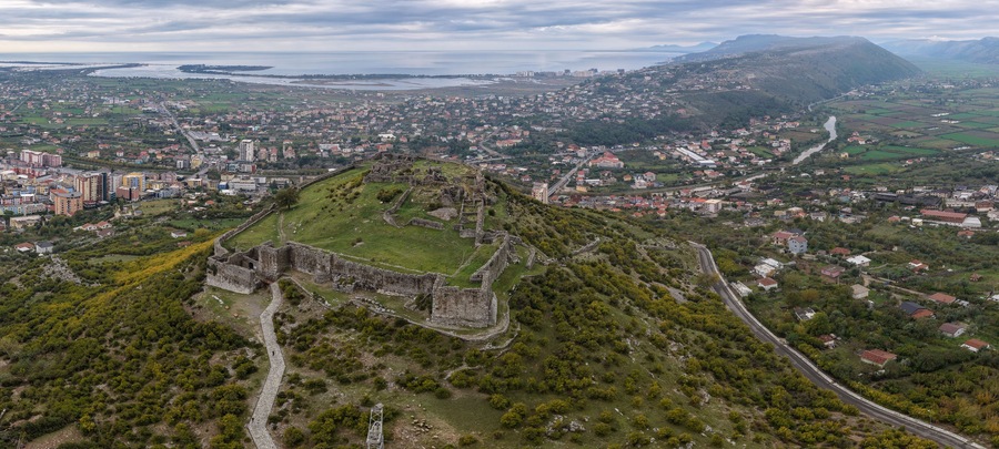 Aerial panorama of Lezhë Castle overlooking the city, Drin River and Adriatic coastline under soft cloudy light.