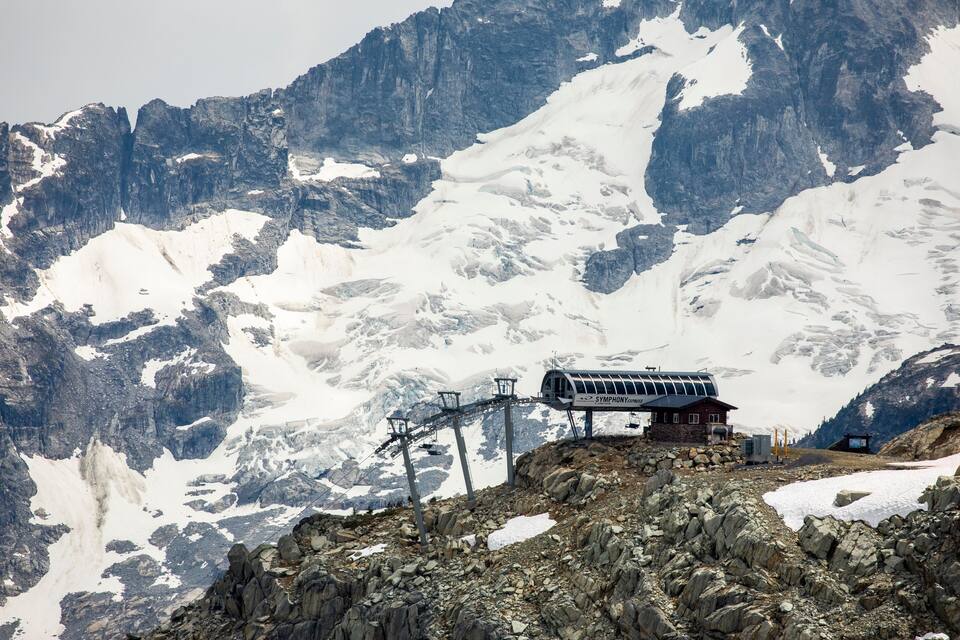 A mountain with a ski lift and a cabin.