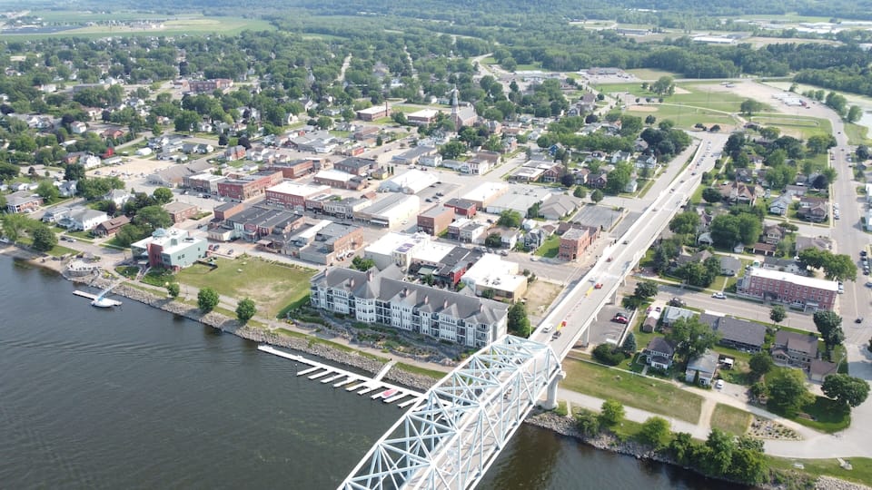 A river with a bridge, a town with houses, and a large building with a tower.