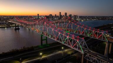 Aerial view of a majestic truss bridge adorned with vibrant red and green lights, spanning dark waters under a twilight sky, Freeport, Texas, United States.