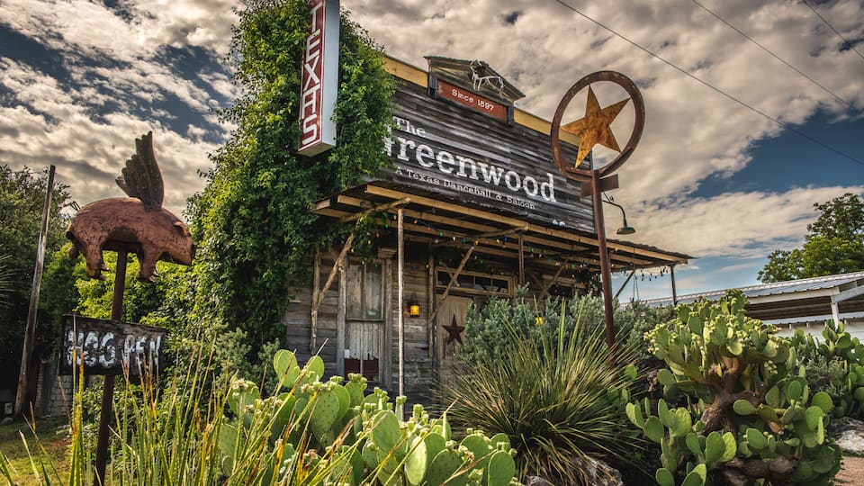 A rustic building with a star sign and a cactus garden.