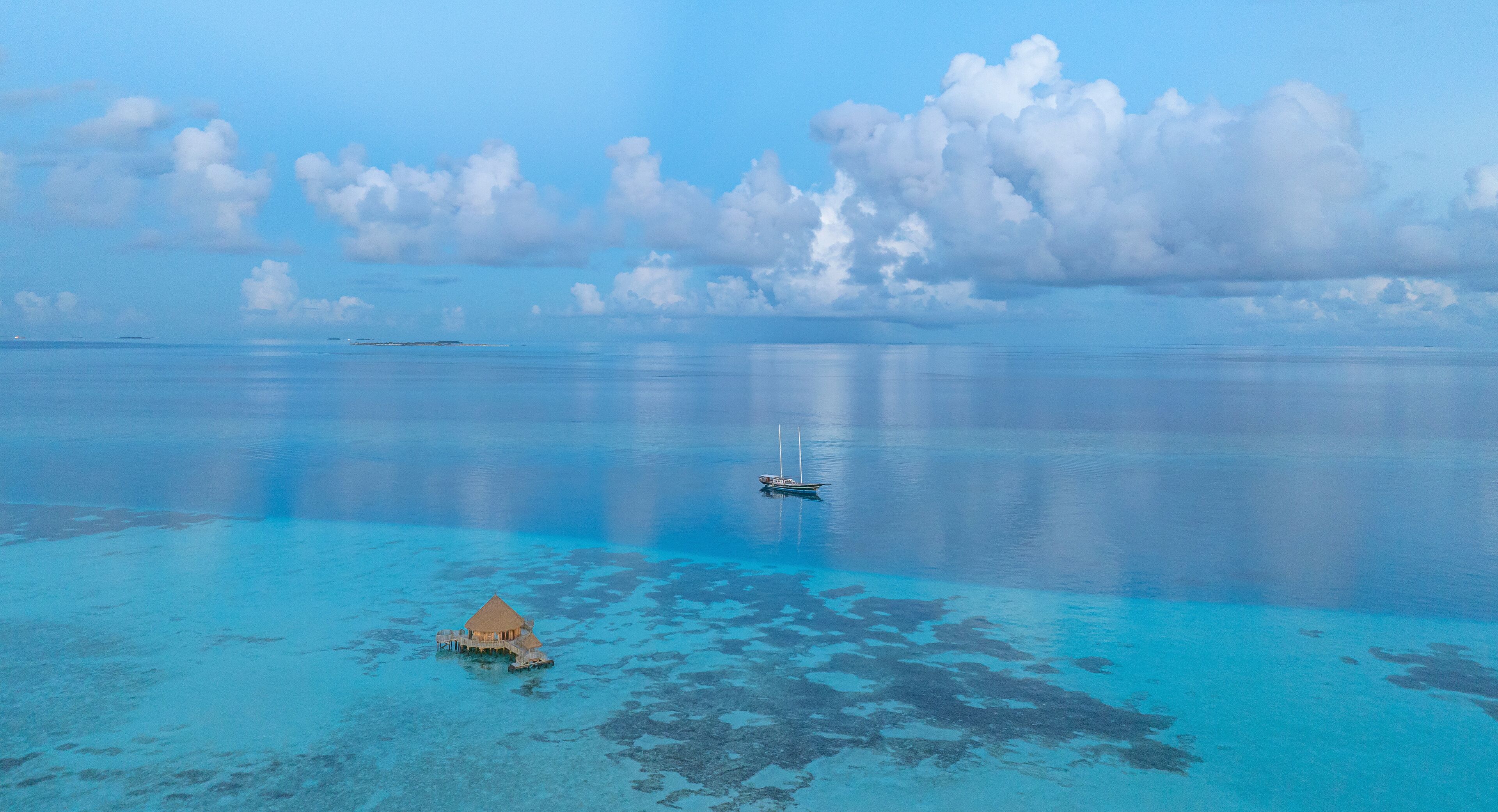 A turquoise sea with a small island and a boat.