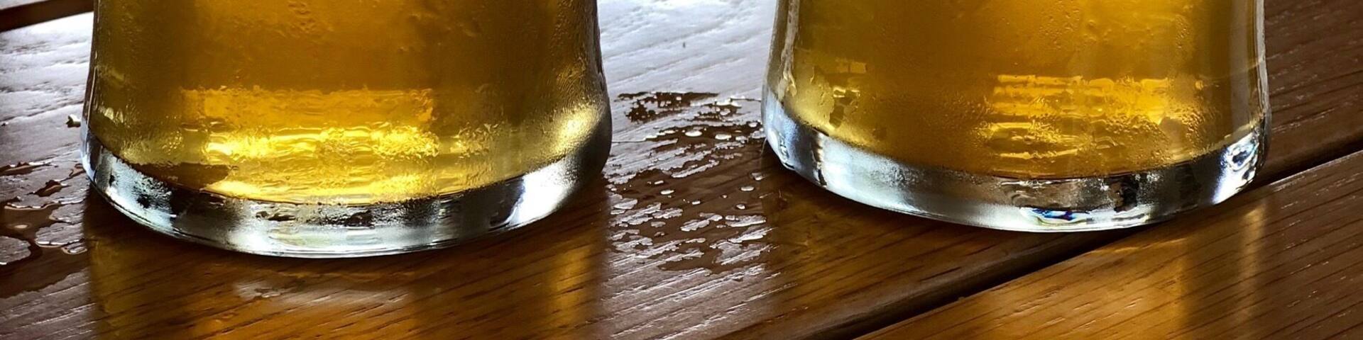 Two glasses of beer with the label 'GOSHEN brewing co' on a wooden table.