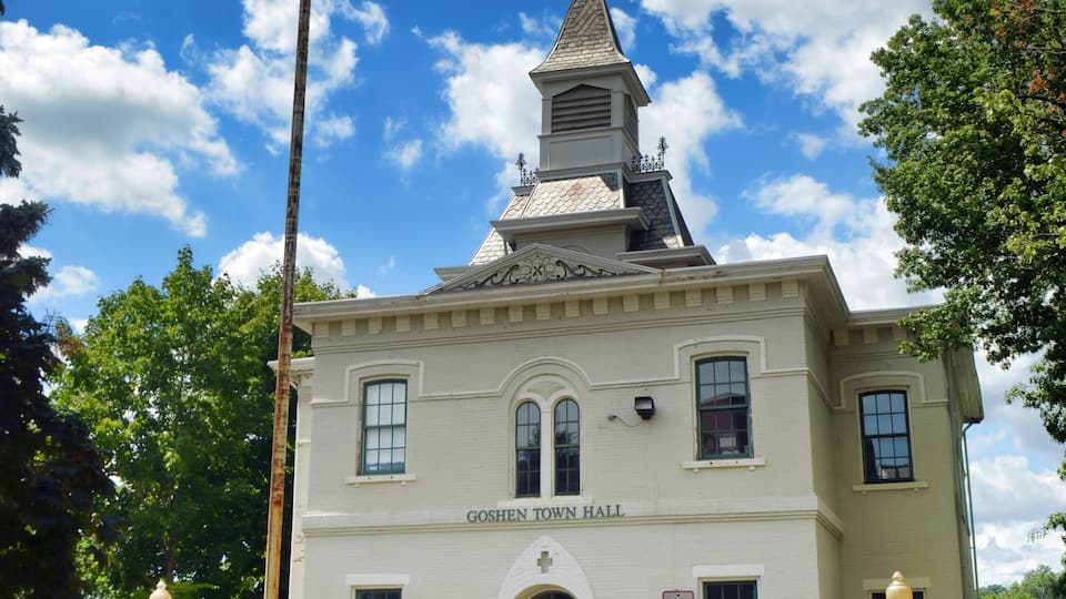 A building with a steeple, an American flag, and the text 'GOSHEN TOWN HALL 41.'