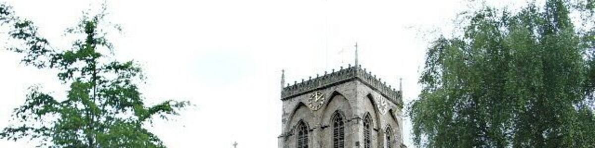 Eine historische Steinkirche mit hohem Turm und Rundbogenfenstern.