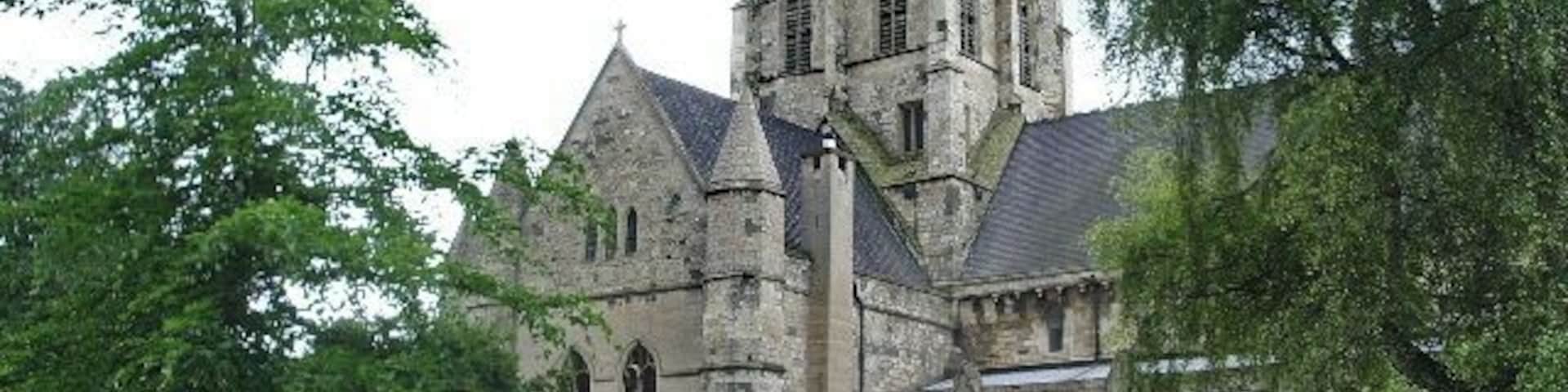 A historic stone church with a tall tower and arched windows.