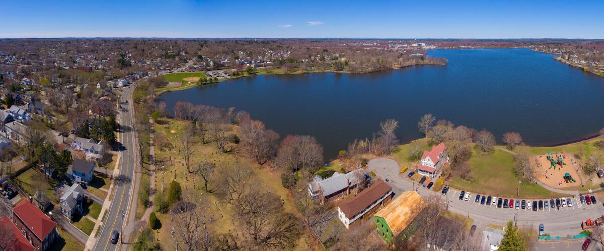 A large lake surrounded by residential areas, a park with a playground, and a road with parked cars.