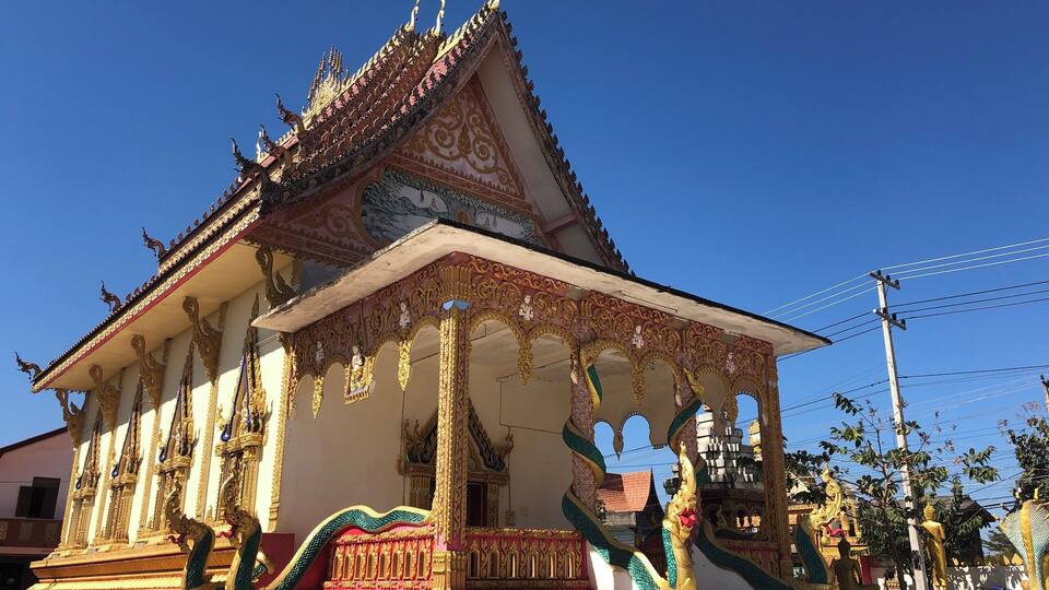 A traditional Thai temple with ornate golden decorations and a pointed roof.
