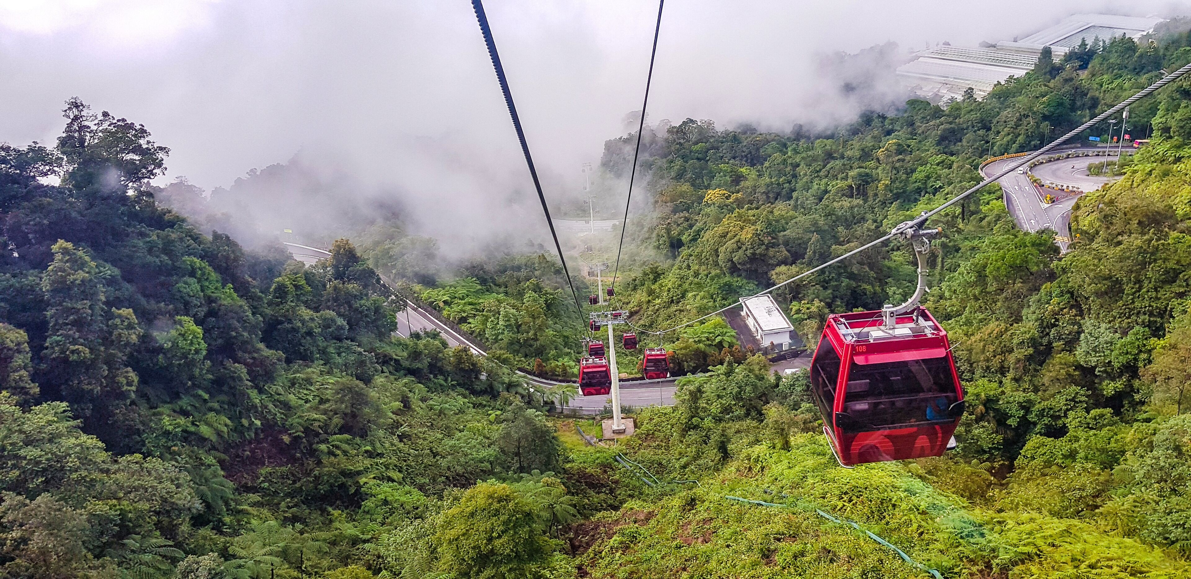 cable car at genting highlands, malaysia in a foggy weather with green grass visible from inside cable car