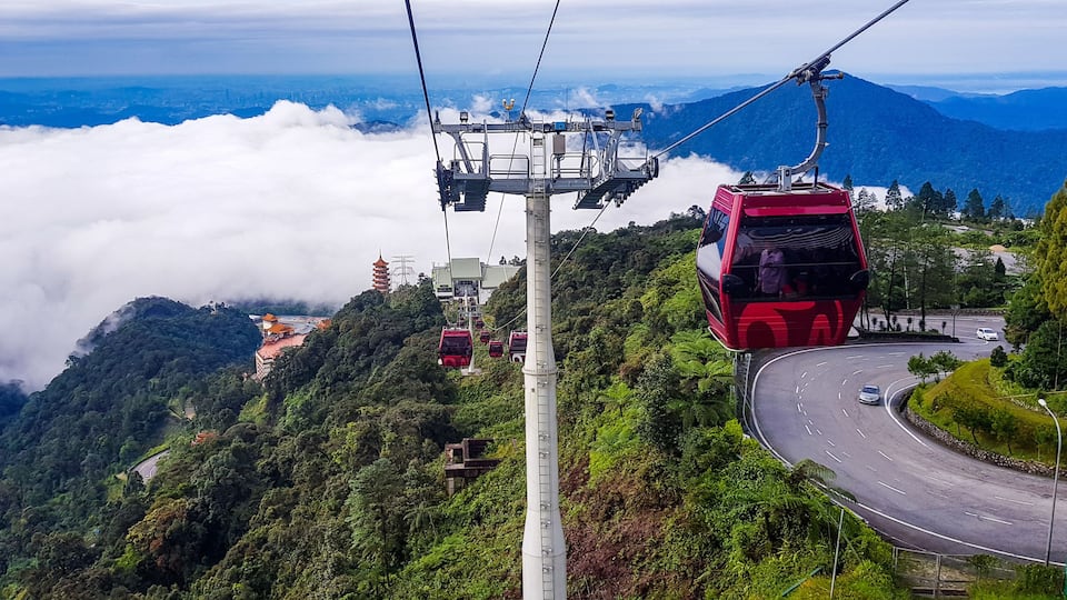 A cable car system, a winding road, and a mountainous landscape with a temple.