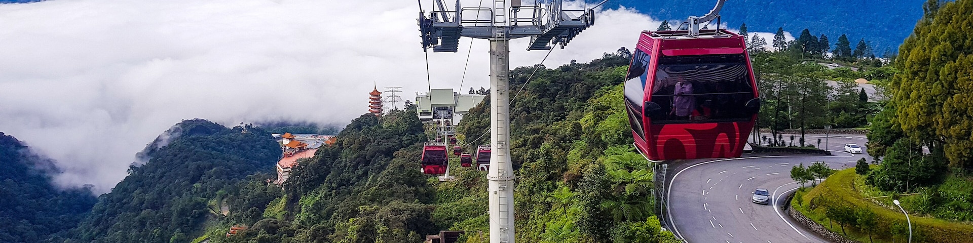 A cable car system, a winding road, and a mountainous landscape with a temple.