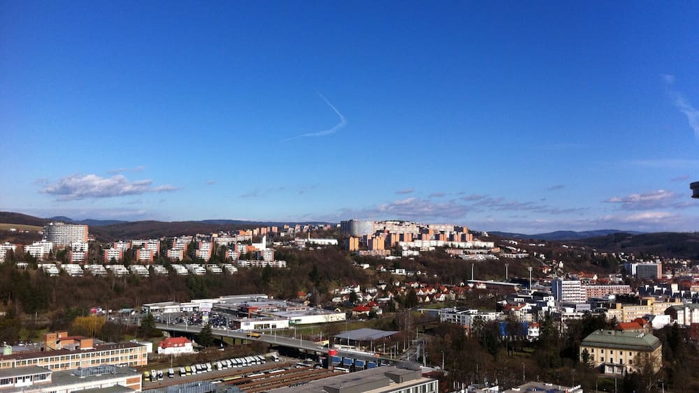 Un paysage urbain avec une colline bien visible, divers bâtiments et un ciel bleu dégagé.