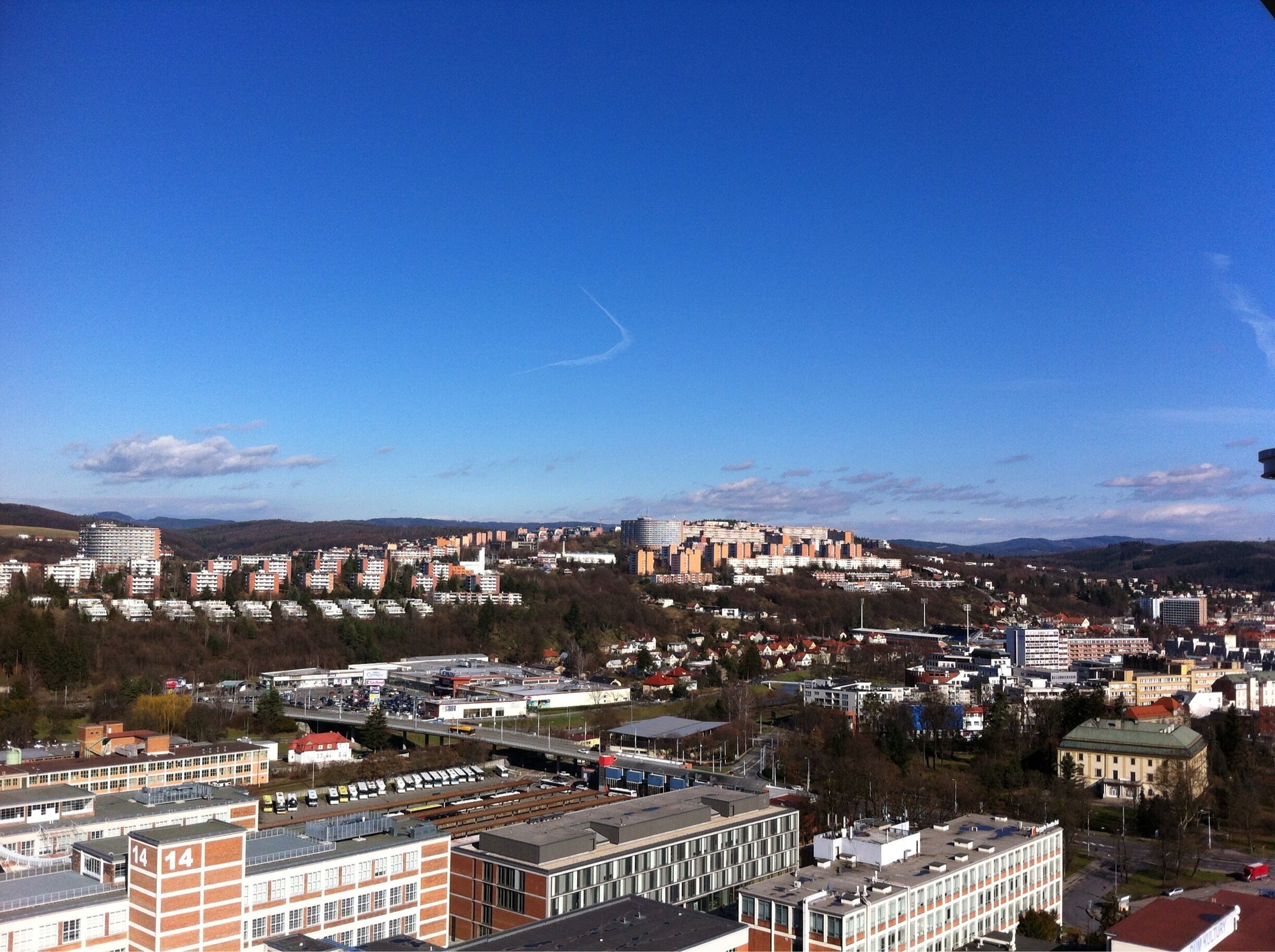 A cityscape with a prominent hill, various buildings, and a clear blue sky.