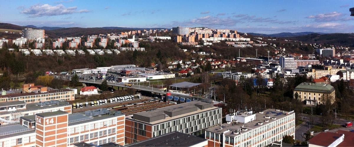A cityscape with a prominent hill, various buildings, and a clear blue sky.