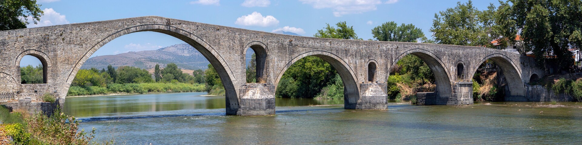 The Bridge of Arta. A stone bridge that crosses the Arachthos river in the west of the city of Arta in Greece. Sunny day with blue sky