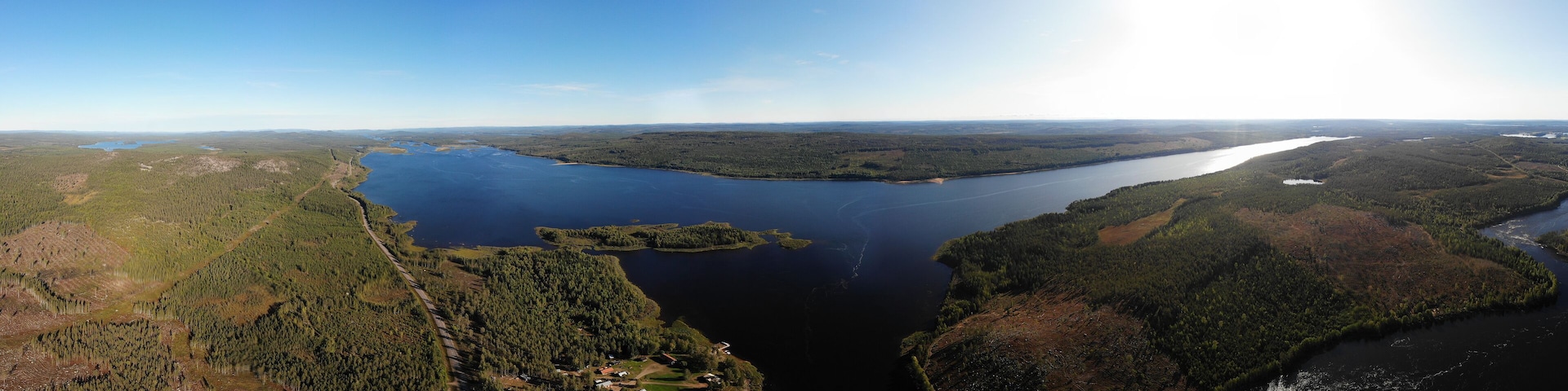 View of Kalix river, Kalixalven, Overkalix locality and the seat in Norrbotten county, Sweden, with forest in sunny summer day, aerial drone view