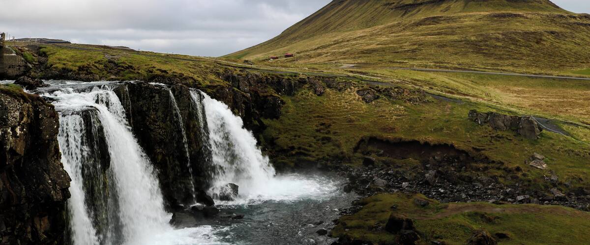 A waterfall, a grassy hill, and a road.