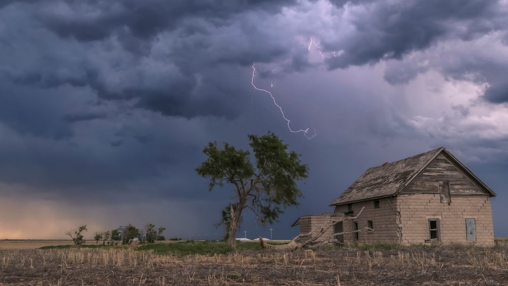 A forked lightning bolt descends from a weak thunderstorm near an abandoned building; Guymon, Oklahoma, United States of America