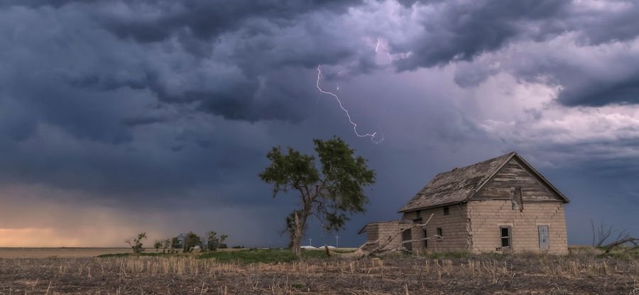 A forked lightning bolt descends from a weak thunderstorm near an abandoned building; Guymon, Oklahoma, United States of America