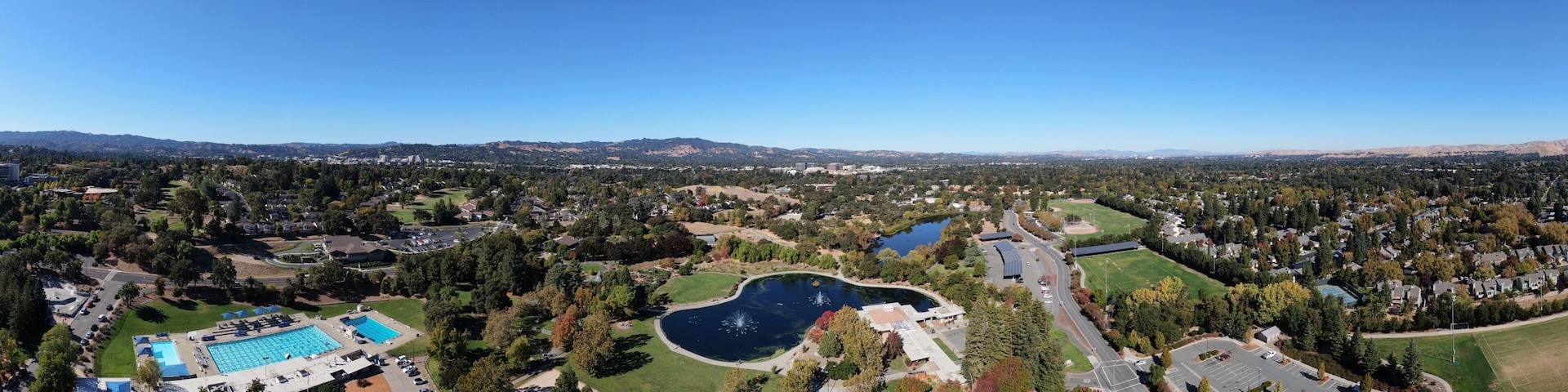 Un parque grande con piscina, lago y campo de golf.