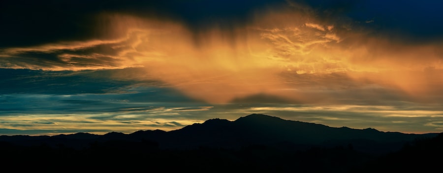 Cordillera recortada contra un cielo al atardecer con formaciones nubosas espectaculares.
