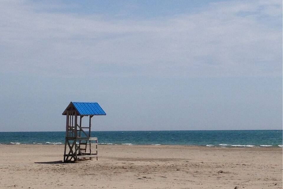 A beach with a lifeguard tower and the ocean in the background.