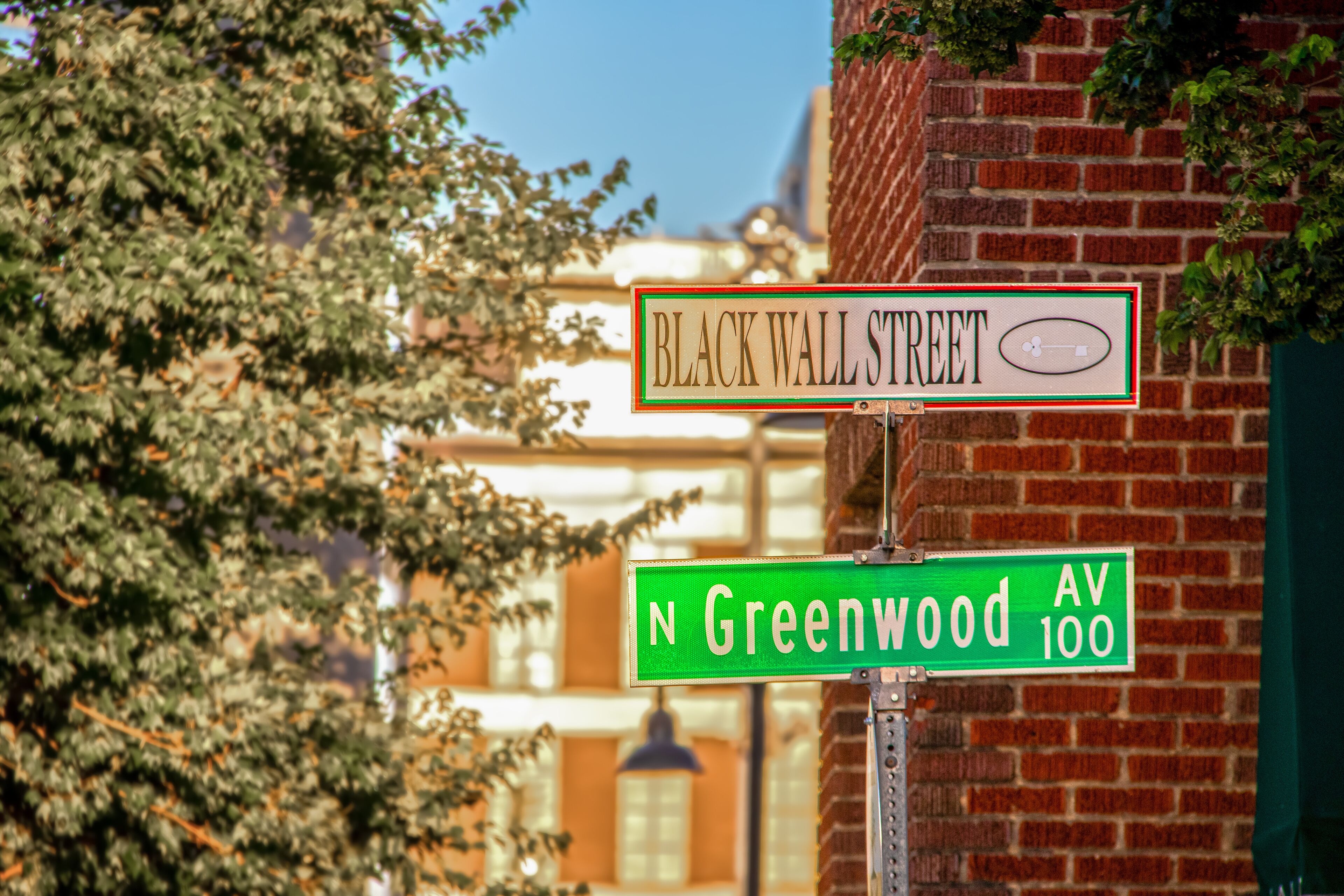 Black Wall Street and N Greenwood Avenue street signs - closeup - in Tulsa Oklahoma with bokeh background