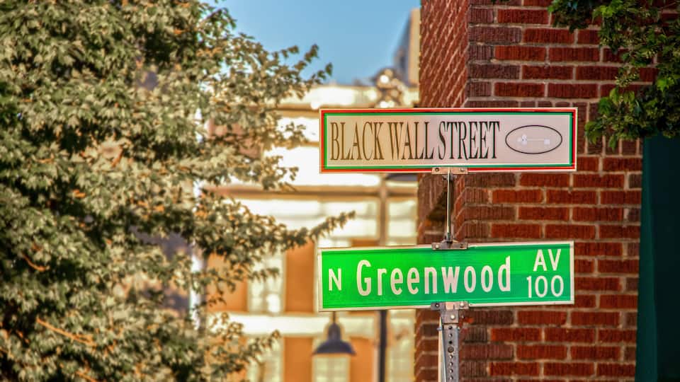 Street signs for Black Wall Street and N Greenwood Av 100.