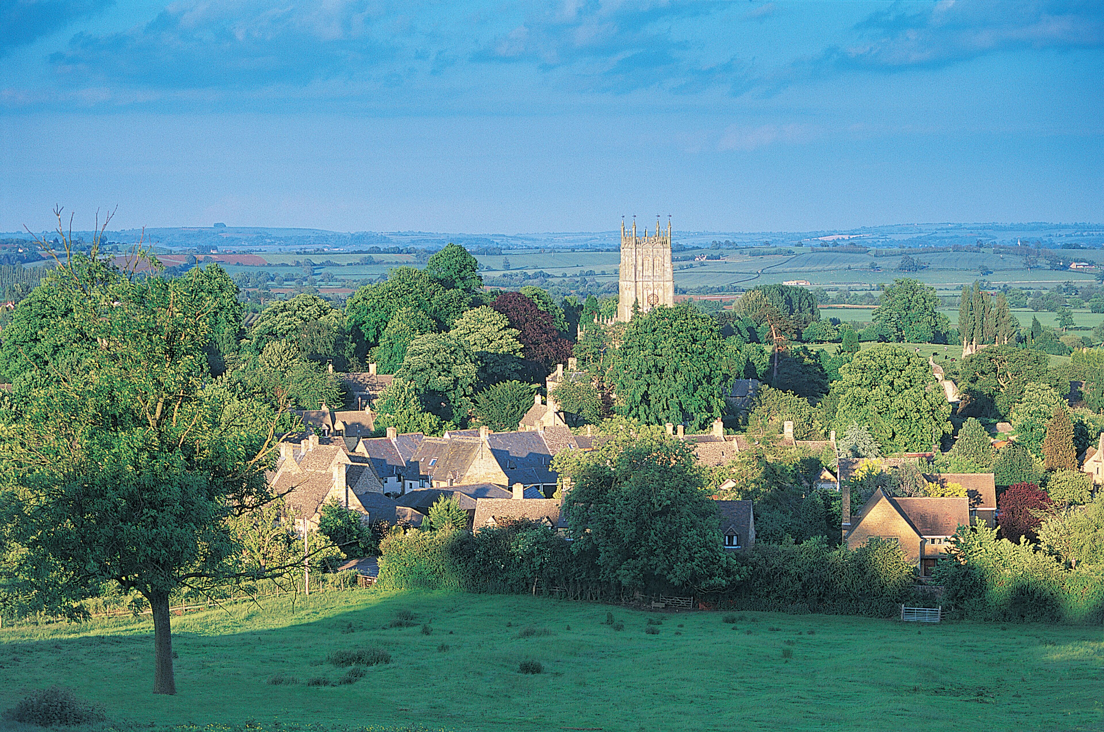 A rural village with houses, a church, and rolling hills in the background.
