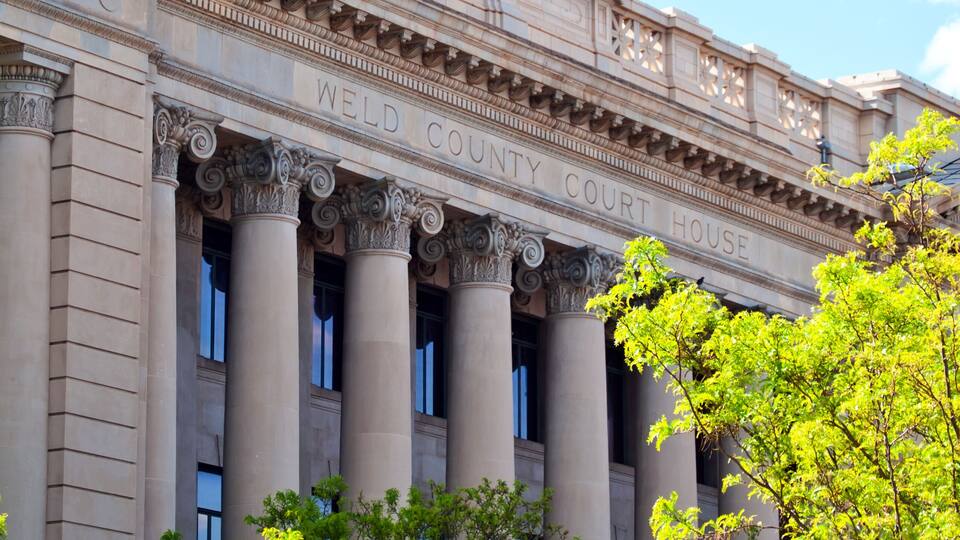 A neoclassical building with a clock tower, columns, and a flag.
