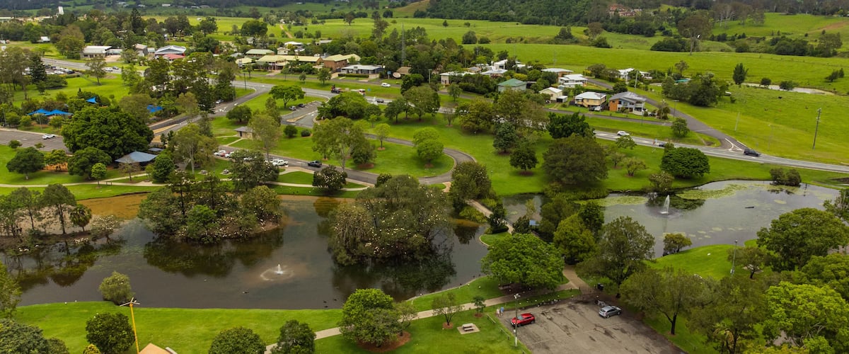 A rural landscape with a pond, green fields, and scattered houses.