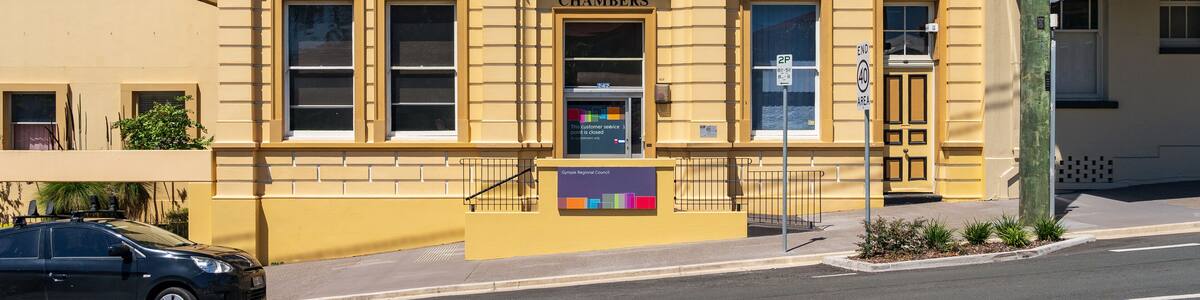 A colorful sunlit historic building on the side of a sloping street