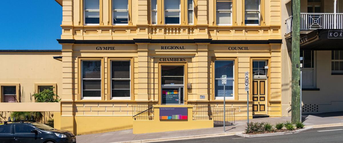 A colorful sunlit historic building on the side of a sloping street