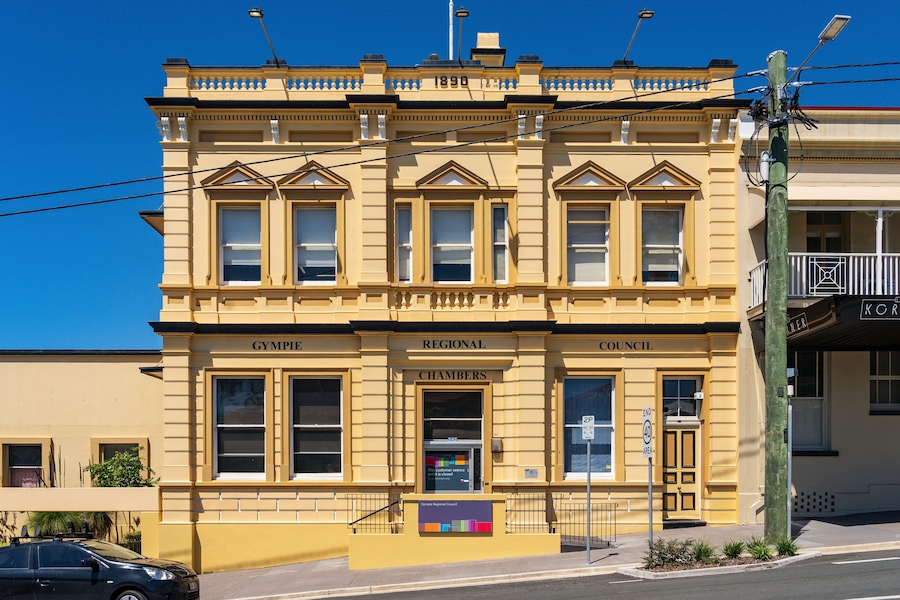 A colorful sunlit historic building on the side of a sloping street