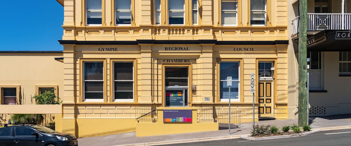 A colorful sunlit historic building on the side of a sloping street