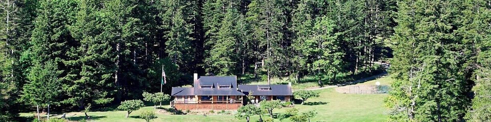 A cabin surrounded by dense forest and a lake.