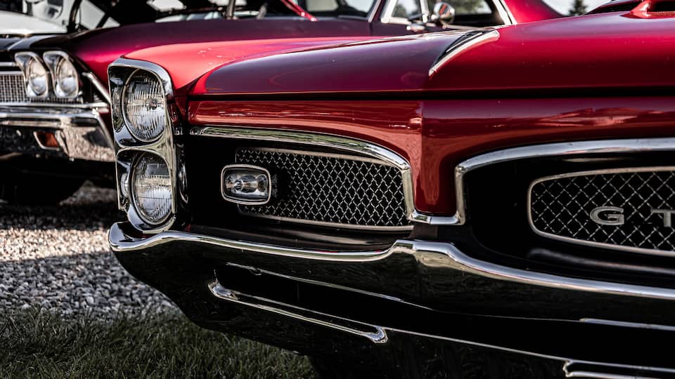 A classic red car with a prominent front grille and chrome detailing.