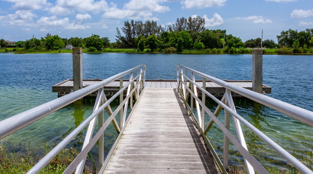 Ramp to boat dock on blue green lake with trees, vegetation and blue sky - Vista View Park, Davie, Florida, USA