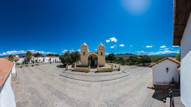 A plaza with a central building, surrounded by cobblestone streets and white buildings with red-tiled roofs.