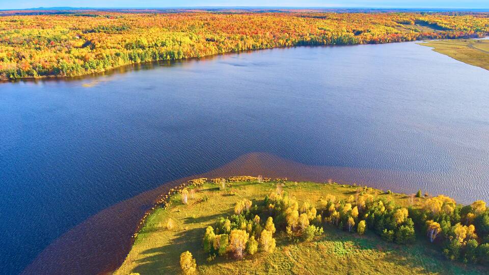 A river winding through a forest with autumn foliage.