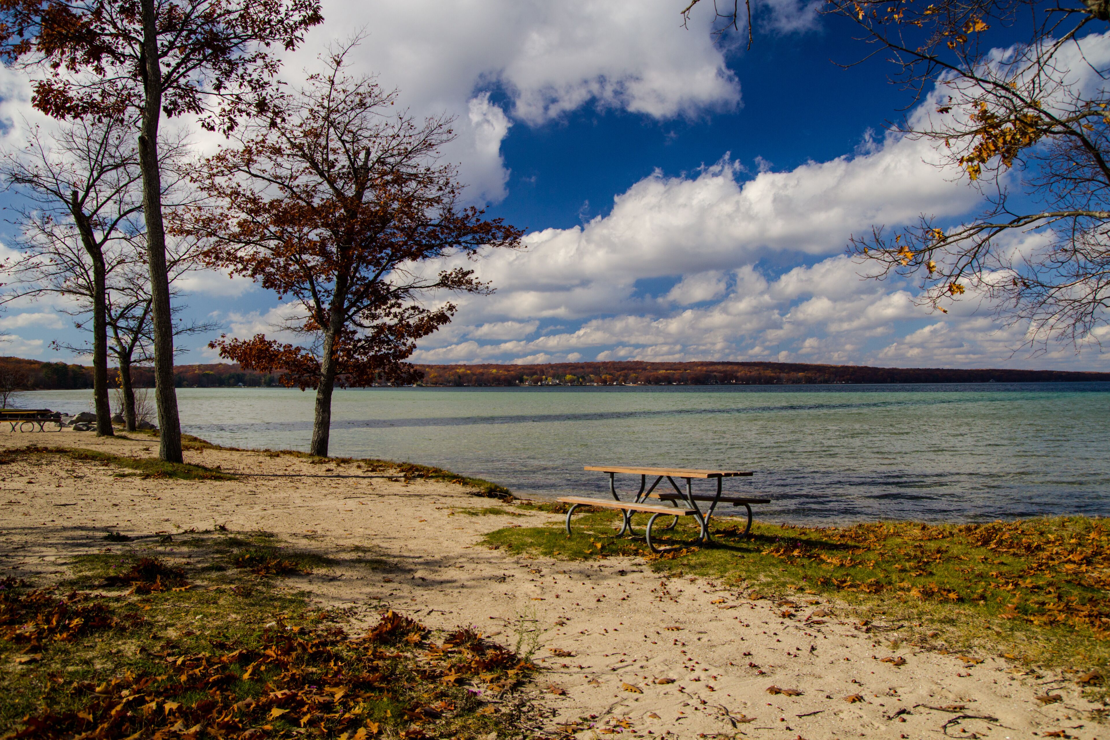 Sunny autumn day on empty beach with picnic table at Higgins Lake State Park in Michigan. 